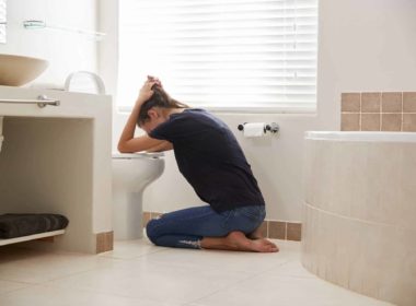Woman Suffering With Morning Sickness In Bathroom At Home