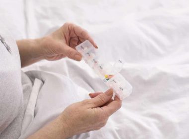 Senior woman taking medication from pill box in bed