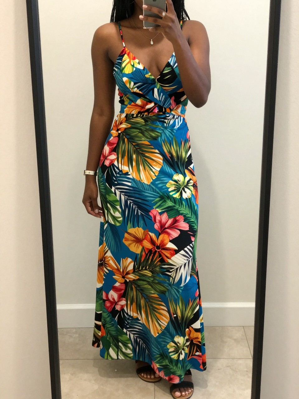 iPhone mirror selfie of a black woman in a tropical print maxi dress and sandals, phone held low to show full dress, cropped at NECK so face doesn't show, iPhone photo quality.
