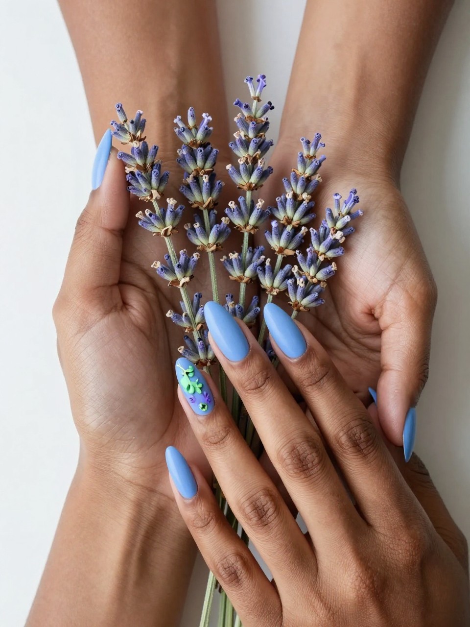 Bird's-eye view of black feminine hands with almond nails gently holding fresh lavender. The nails are a matte sky blue. A single, finely detailed lavender sprig is painted on each nail in soft purple and green. The lighting is bright and airy.