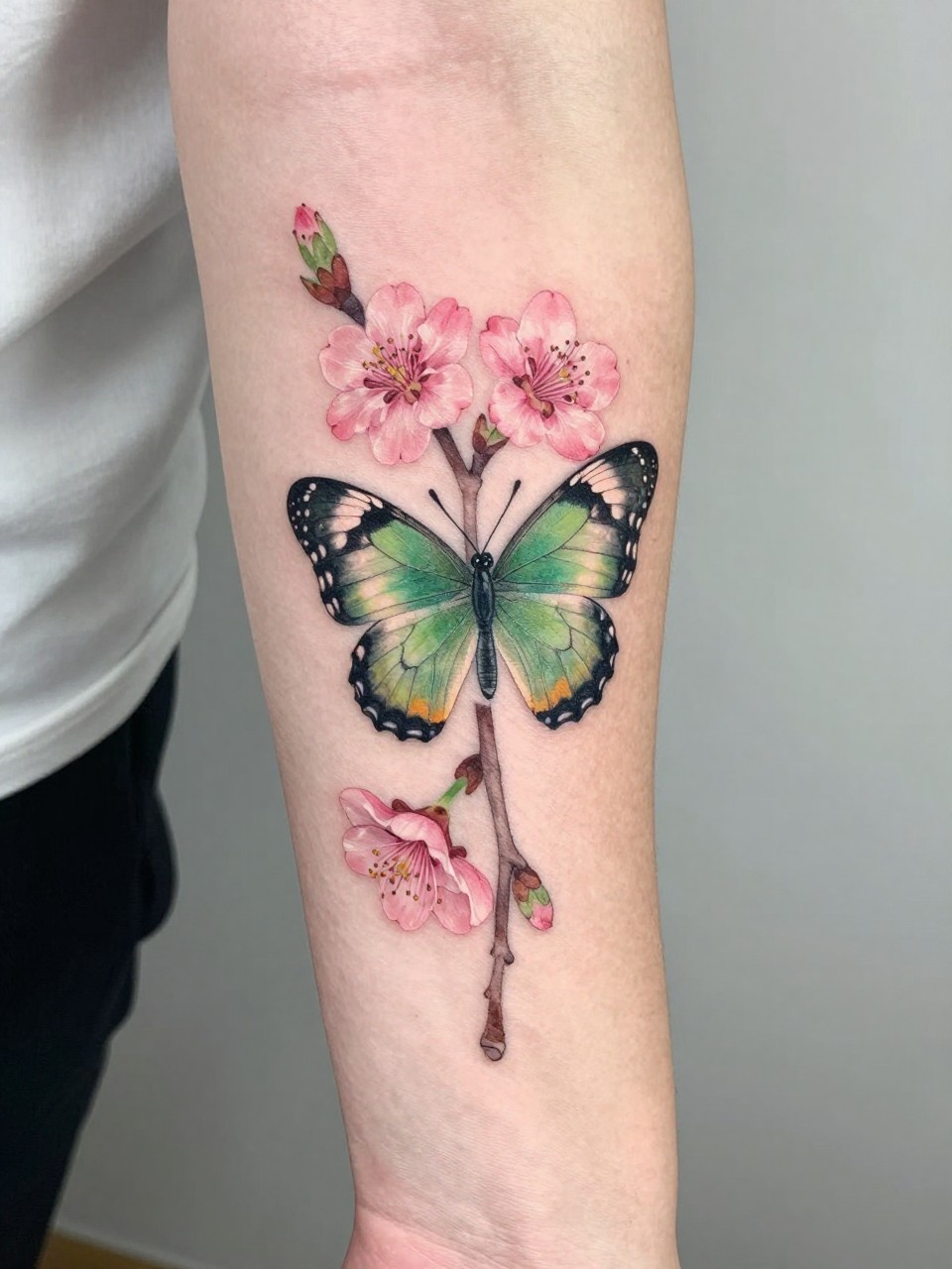 Mid-forearm section tattoo: spring segment with a butterfly drying its new wings on a cherry blossom branch. Soft pinks and fresh greens, symbolizing new beginnings."