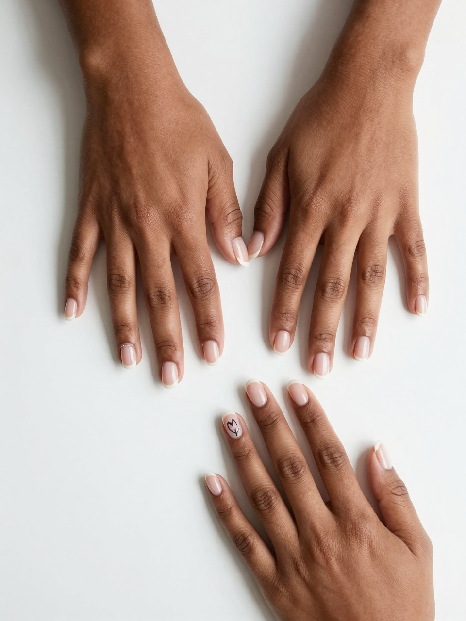 Overhead view of a black feminine bride’s hands with perfectly groomed natural nails on a clean white surface. On one nail design only, a single, continuous black line forms a simple tulip outline. The rest are bare. The aesthetic is modern, gallery-like, and confident.