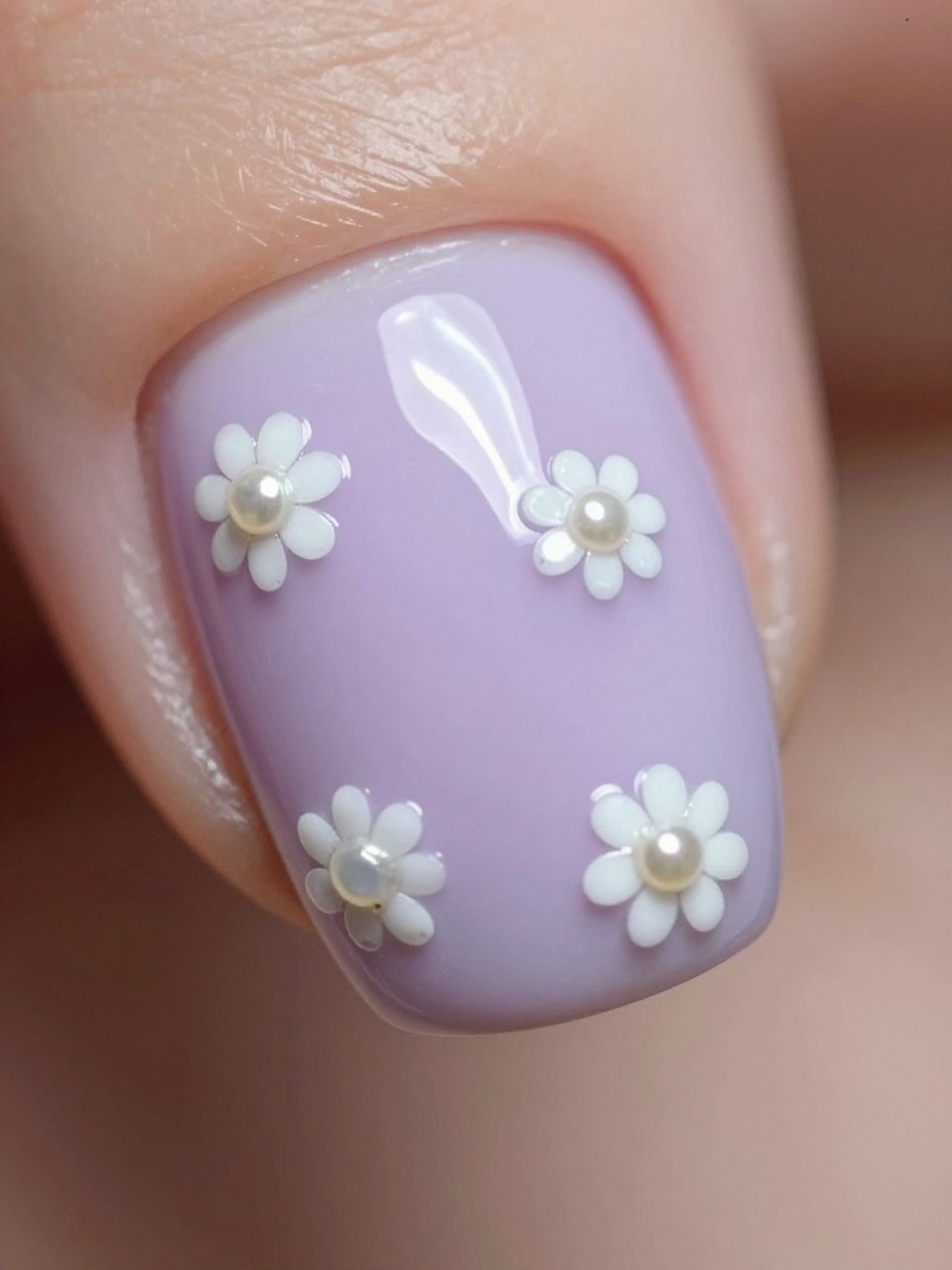 Macro, top-down view of a nail. The base is a milky lavender. Tiny white daisy sequins and micro pearl hearts are scattered and sealed under a glossy layer. The effect is gentle, precious, and tactile.