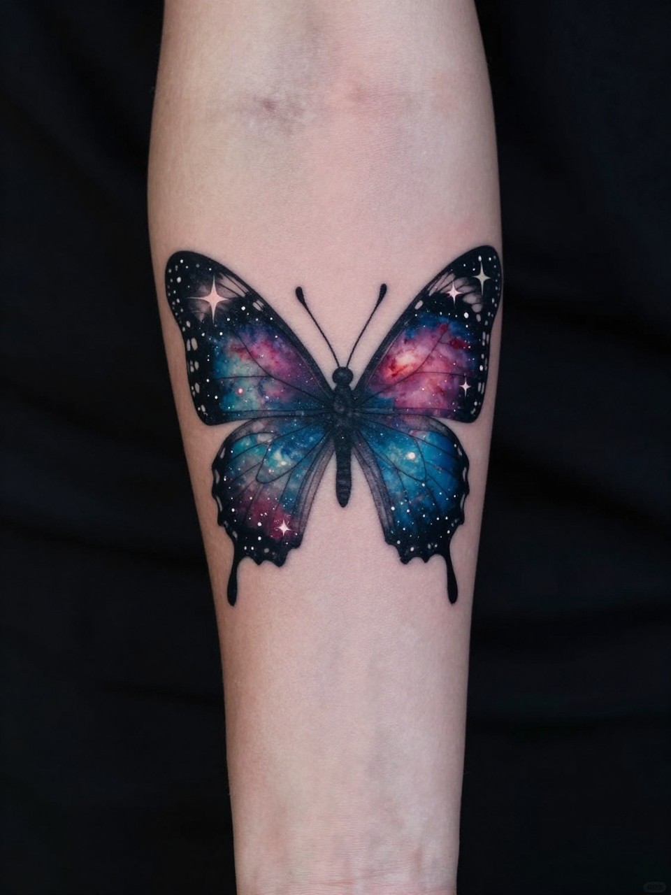 View of a lower arm sleeve tattoo: a butterfly with wings made of a nebula, stars dotting its outline, against a deep space background. Cosmic and magical."