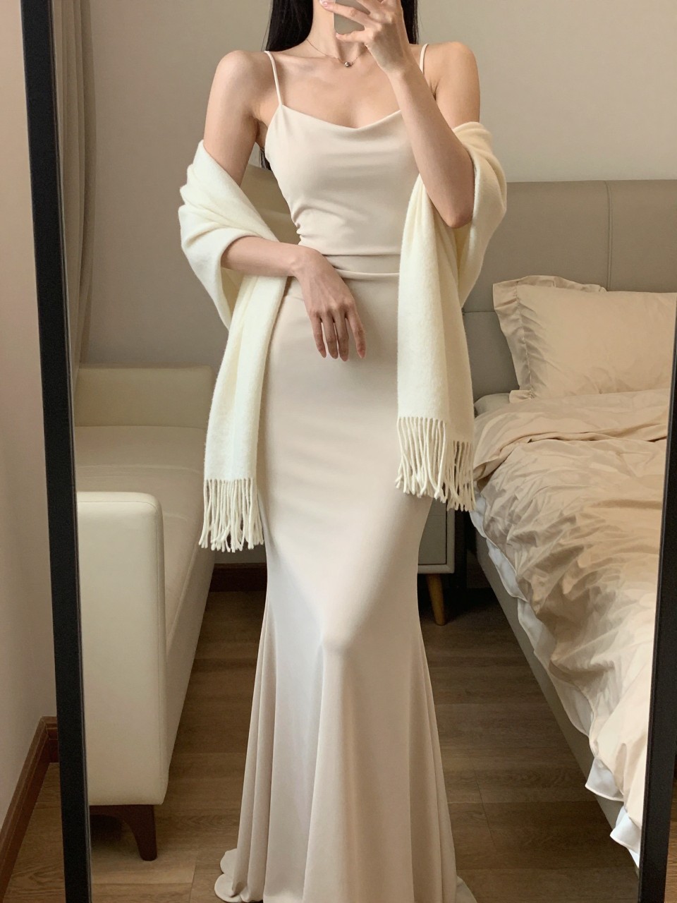mirror selfie of a woman in a column gown with a shawl draped over her arms, posing gracefully, cropped at NECK so face doesn't show, in a feminine-themed bedroom, warm moody lighting, iPhone photo quality.