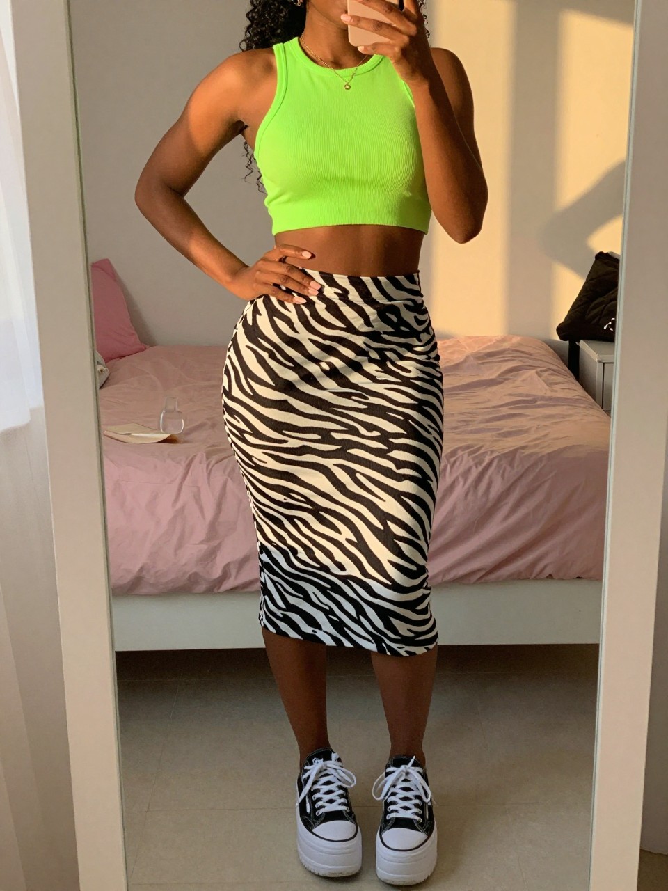 mirror selfie of a black woman in a neon green crop top and a zebra print high-waisted skirt with platform sneakers, one hand on her hip, cropped at NECK so face doesn't show, in a feminine-themed bedroom, evening golden hour, iPhone photo quality.