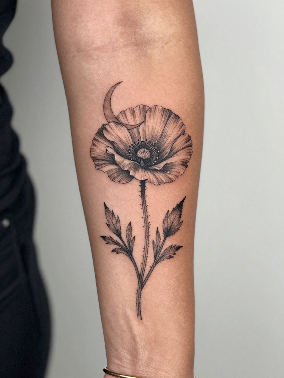 Image Prompt: "Close-up of a poppy flower tattoo with a crescent moon on the inner arm of black feminine woman, black ink fine line floral design, open petals, soft shading, delicate celestial accent, realistic skin texture, gold bracelet lightly visible, feminine modern tattoo inspiration photo, clean soft background, tattoo is the main subject (no watermarks on images)"