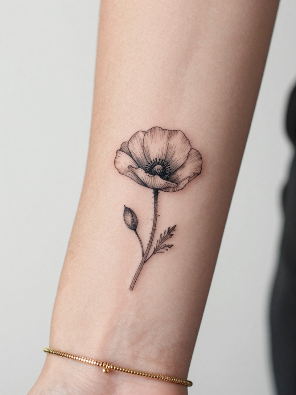 Image Prompt: "Macro shot of a tiny poppy flower tattoo on the inner wrist, black ink fine line floral design with soft petal detail and light shading, minimalist style, realistic skin texture, delicate gold bracelet, tight crop, feminine tattoo inspiration image, clean minimal background, tattoo-centered composition (no watermarks on images)"