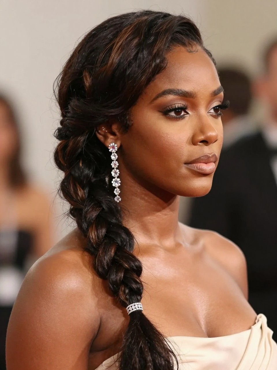 A photorealistic hairstyle portrait showing a black woman in loose side braid draped over one shoulder, softly textured hair with subtle highlights, a crystal earring chain connecting the ear to the upper section of the braid, soft glam makeup, feminine event dress, softly blurred background, editorial beauty lighting, no text, no watermark, no watermarks on images.