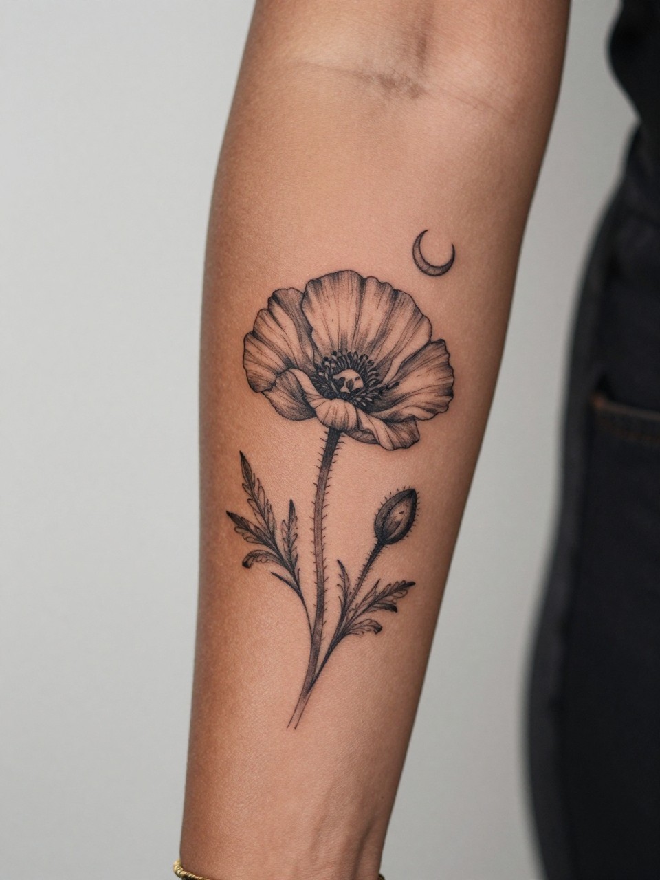 Image Prompt: "Design-focused close-up of a poppy tattoo with a tiny crescent moon on the inner arm of a black woman, black ink fine line floral design, soft petal shading, delicate celestial accent, realistic skin texture, gold bracelet lightly visible, feminine modern tattoo inspiration photo, clean soft background, tattoo is the hero (no watermarks on images)"