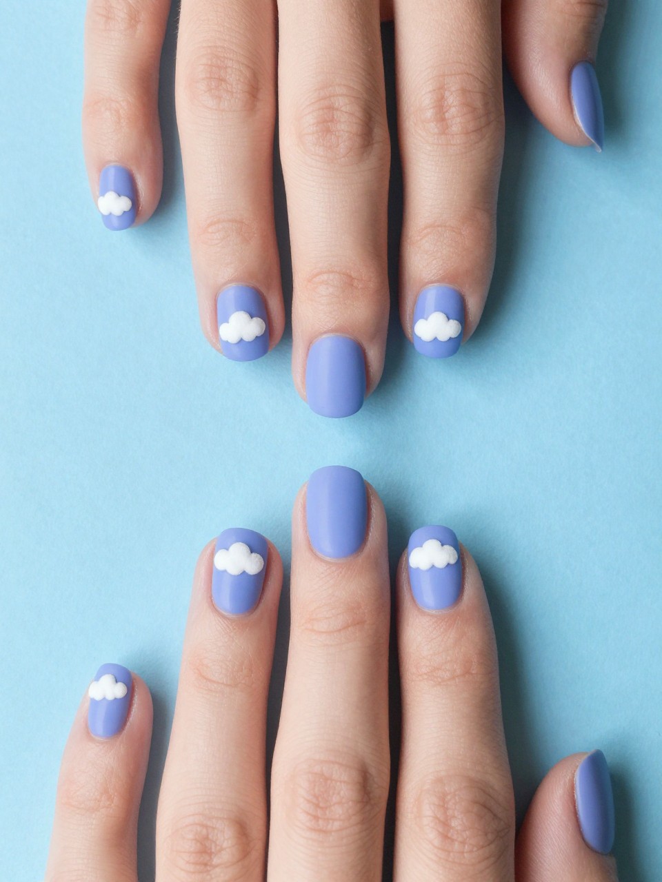 Image Prompt: Bird's-eye view of hands with short, rounded nails against a blue backdrop. The nails are a matte periwinkle blue-purple. Each nail has a small, fluffy white cloud design on the nails tip. The overall feel is dreamy and light.