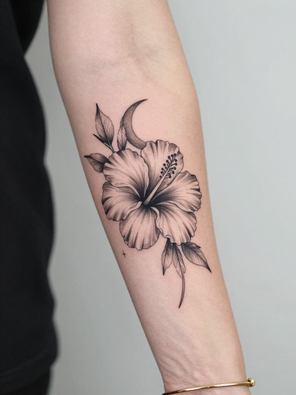 Image Prompt: "Close-up of a hibiscus flower tattoo with a crescent moon on the inner arm, black ink fine line floral design, open petals, soft shading, delicate celestial accent, realistic skin texture, gold bracelet lightly visible, feminine modern tattoo inspiration photo, clean soft background, tattoo is the main subject (no watermarks on images)"