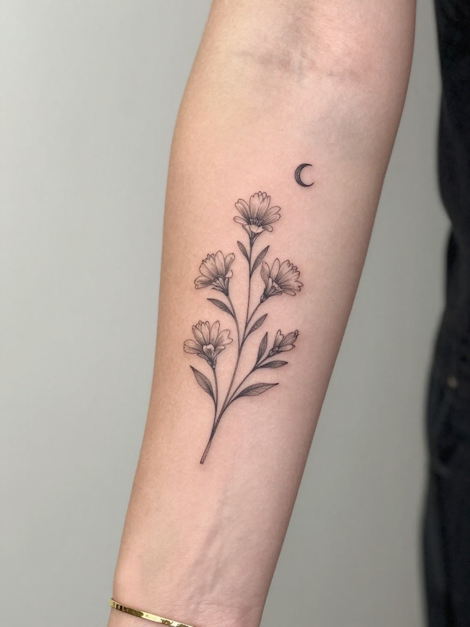 Image Prompt: "Design-focused close-up of a sampaguita tattoo on dark with a tiny crescent moon on the inner arm, black ink fine line floral design, delicate small blooms, soft shading, delicate celestial accent, realistic skin texture, gold bracelet lightly visible, feminine modern tattoo inspiration photo, clean soft background, tattoo is the hero (no watermarks on images)"
