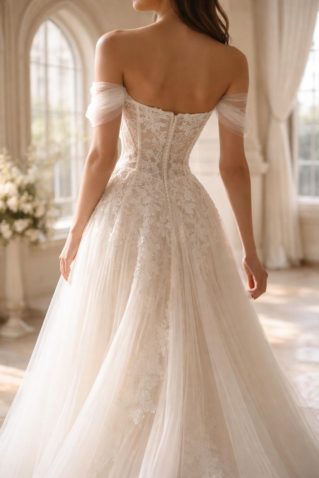 Image Prompt: A luxury bridal editorial image of a lace corset wedding dress in a romantic chapel or elegant bridal suite. Show the bride cropped from the neck down or from behind with the face fully hidden. The gown features a fitted corset bodice with delicate lace overlay, soft boning detail, a defined waist, and a flowing skirt with a light train. Use soft daylight, realistic lace texture, refined bridal styling, professional magazine-quality photography, no visible face, no text, no watermark. (no watermarks on images)
