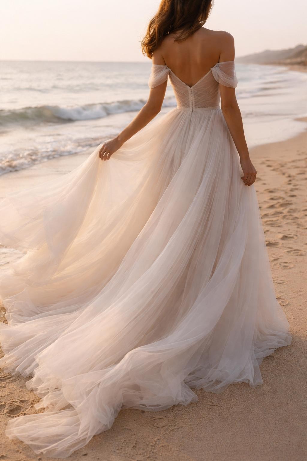 Image Prompt: A high-end bridal editorial photo of a flowing chiffon beach wedding dress on a quiet shoreline at golden hour. Show the bride from the neck down only, or from a back three-quarter angle so the face is fully hidden. The gown has a light chiffon bodice, soft waistline, airy skirt, and gentle movement in the ocean breeze. Use natural sunlight, pale sand, calm waves, realistic chiffon texture, elegant bridal styling, luxury magazine-quality photography, no visible face, no text, no watermark. (no watermarks on images)
