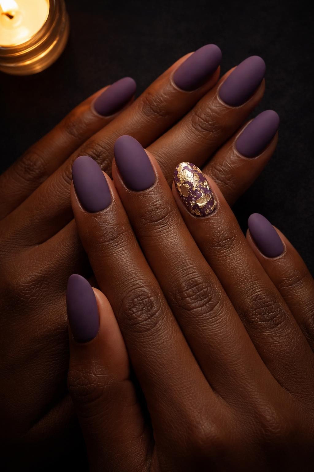 Image Prompt: Close-up, top-down view of black feminine hands with rounded nails against a dark background. The base is a deep matte amethyst. On the ring fingers, delicate, fragmented pieces of gold leaf are scattered. Candlelight makes the gold leaf glimmer.