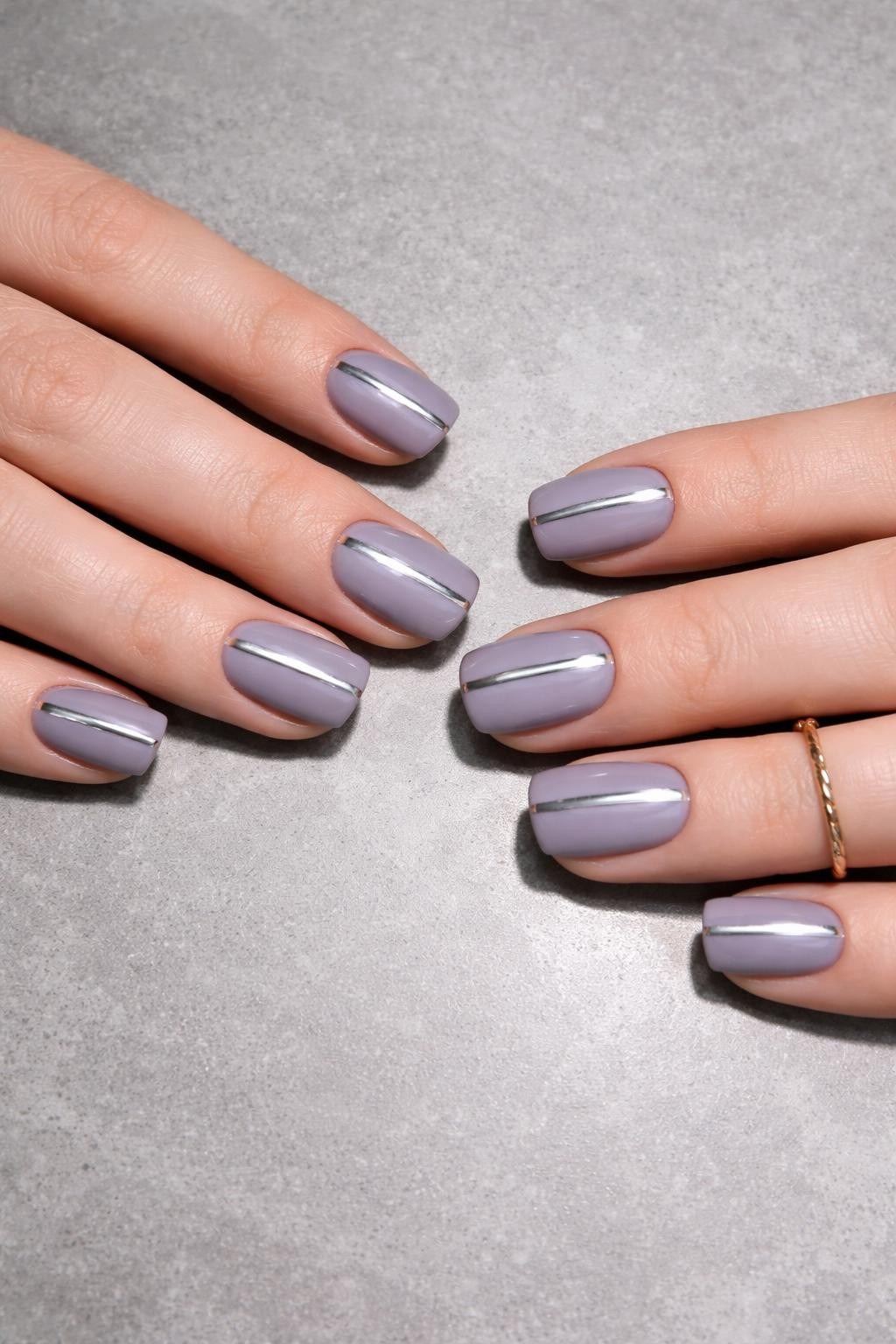 Image Prompt: Overhead, top-down view of feminine hands with short, square nails resting on a smooth, grey stone surface. The nails are a muted, matte lavender. Two thin, mirror-like chrome lines run vertically down each nail. The lighting is bright and cool, making the chrome shine.