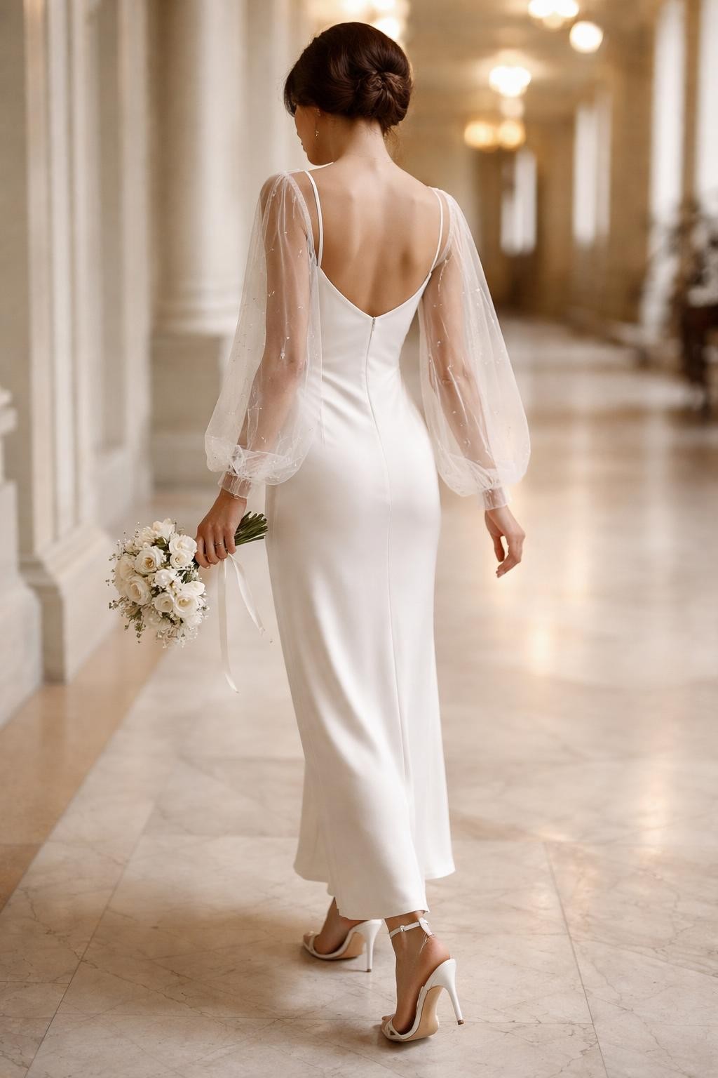 Image Prompt: A professional bridal editorial image of a white slip dress styled with a sheer bolero in a bright courthouse hallway or elegant city hall room. Show the bride from the neck down or from a back three-quarter angle so the face is completely hidden. The slip dress has a slim satin or crepe shape, while the bolero has sheer sleeves, delicate embroidery, or pearl accents. Style with simple heels, a small bouquet, soft natural light, realistic fabric texture, polished bridal editorial quality, no visible face, no text, no watermark. (no watermarks on images)