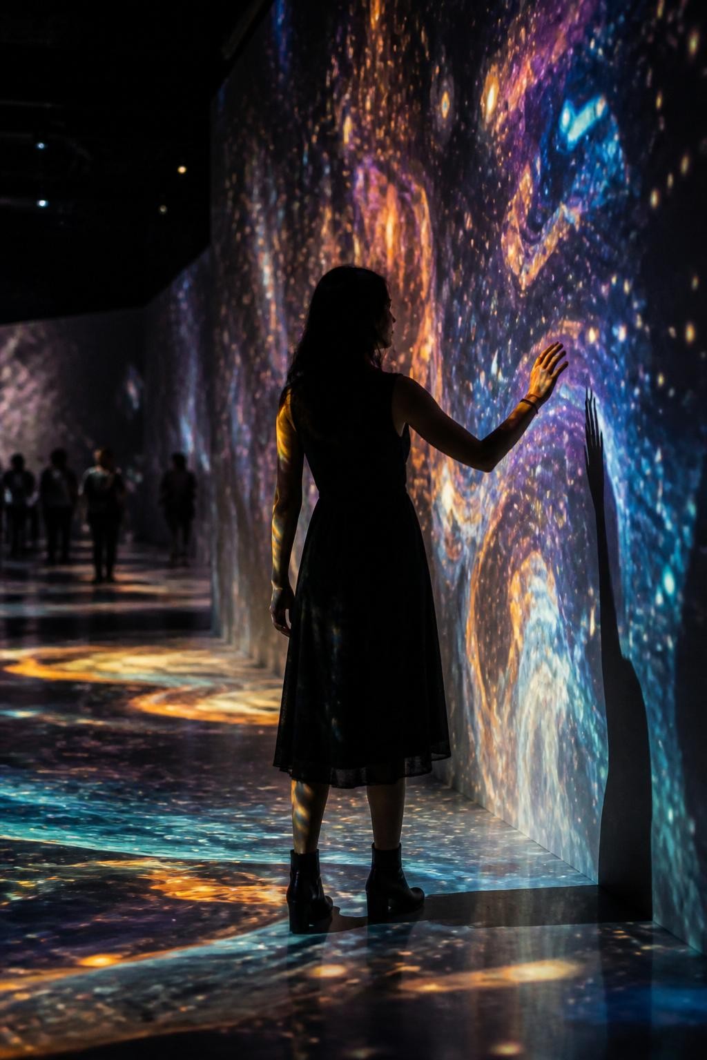 Image prompt: A cinematic DSLR museum photo of an adult woman with medium skin tone standing inside a dark digital art projection room, shown mostly in silhouette with her face not clearly visible, wearing a simple black dress and ankle boots, standing with one arm slightly lifted toward the moving light on the wall, colorful projected shapes across her body and the floor, other visitors softly blurred far behind her, dark room, soft haze, realistic light spill, artistic museum installation mood, modern travel photography, no direct camera stare.