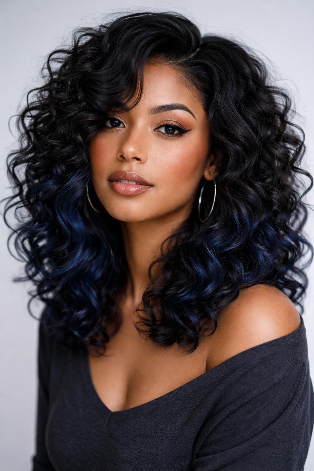 Image Prompt: A stylish woman with shoulder-length curly hair, deep black top layer with midnight blue peekaboo color underneath, defined curls with healthy volume and shine, dark blue hidden sections peeking through the lower curls and sides, medium-deep skin tone, soft neutral makeup, glossy lips, silver hoop earrings, charcoal top, clean studio background, soft cool lighting, realistic DSLR beauty portrait, detailed curl texture and blue-black contrast, no text, (no watermarks on images)
