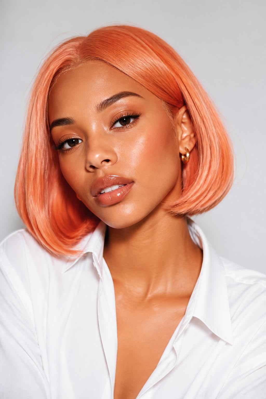 Image Prompt: A chic brown woman with a chin-length coral peach bob, smooth rounded bob shape with a soft bend at the ends, warm coral-peach hair color with glossy shine, fresh natural makeup, glossy lips, small gold earrings, white button-up shirt, bright clean studio background, soft flattering lighting, realistic beauty editorial photography, detailed bob shape and coral peach shine, no text, (no watermarks on images)