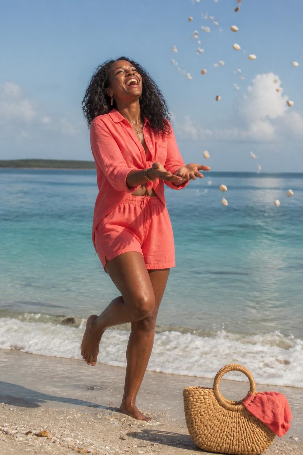 A realistic DSLR beach photo of an adult Black woman with deep brown skin standing near the shoreline in a bright coral linen two-piece beach set, holding a handful of small clean seashells and tossing them gently upward like confetti, her head tilted back in a natural laugh, one foot slightly lifted from the wet sand, soft ocean foam behind her, scattered shells around her feet, sunlight catching the shell edges, wind moving her loose curls, woven beach bag nearby, clear blue water in the background, natural skin texture, slight motion blur in the shells, joyful editorial beach photography, human candid feel.